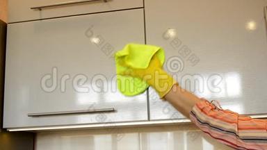 女人`一只黄色的橡胶<strong>手套</strong>，用一块布清洁了现代塑料<strong>厨房</strong>橱柜闪亮的表面。 sp的概念