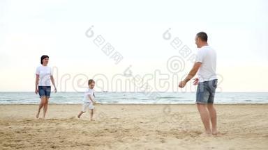 幸福的家庭在沙滩上休息。 快乐的微笑男孩向他父亲跑去。 爸爸在玩耍，他的孩子在长大