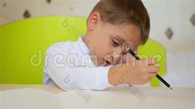 小男孩懒洋洋地手里拿着一支铅笔，在纸上画画，遮住了他的眼睛和脸。 教育和教育