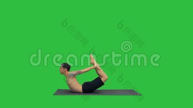 运动肌肉的年轻瑜伽男子做后弯运动，达努拉萨纳，弓姿势在绿色屏幕，铬键。