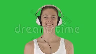 音乐，人与<strong>科技</strong>理念-幸福微笑的女人带着耳机走在绿色的屏<strong>幕</strong>上，色度键。