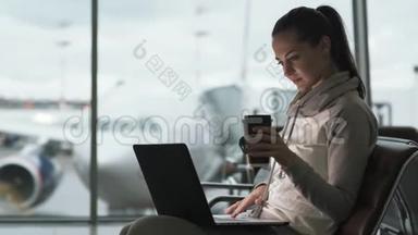 女自由职业者喝外卖咖啡，用笔记本电脑在机场候机室工作