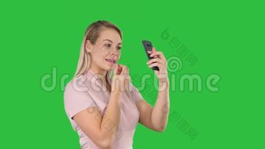 美女，人，化妆，年轻的女人嘴唇看着绿色屏幕上的智能手机，Chroma键。