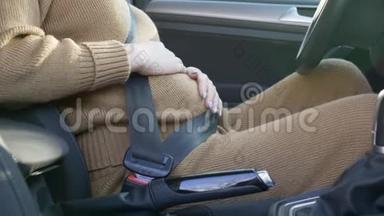 孕妇司机在方向盘后，关心未来的母亲戴着安全带抚摸着肚子，未来的婴儿坐在旁边