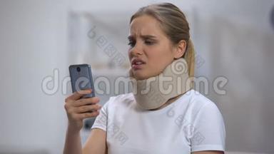 戴泡沫颈<strong>项圈</strong>的女人在手机上读短信，感觉脖子疼