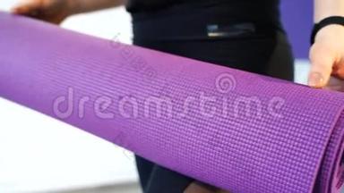 女子手中的紫色瑜伽垫`特写..