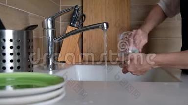 女人的手在厨房水槽里冲洗眼镜-在家里做家务。 洗碗常规，静态摄像头.. 快关门。