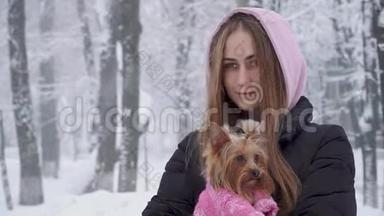 一位留着长发的可爱女孩拥抱着一只穿着羊毛衫的约克郡猎犬，双手抱着一只狗