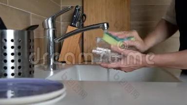 女人的手在<strong>厨房</strong>水槽里<strong>冲洗</strong>眼镜-在家里做家务。 洗碗常规，静态摄像头.. 快关门。