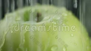 在视频中，我们看到一个绿色的苹果，水开始从顶部像波浪一样倾泻，绿色的背景，特写。