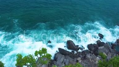 海浪以浪花和白色泡沫破碎到岩石悬崖。 海浪飞溅到岩石岛的顶部。 绿松石