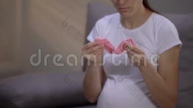 沮丧的怀孕代孕妈妈抱着粉红色的袜子，心理问题