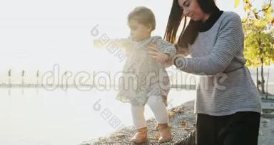 一位年轻的母亲和她的<strong>女儿</strong>在新鲜的空气中散步。 <strong>一家人</strong>在公园夕阳下散步