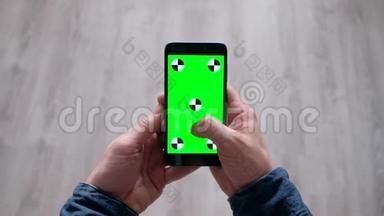 男人的手慢慢地用绿色<strong>屏幕滚动</strong>智能手机上的信息。