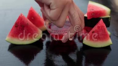 手拿西瓜糖浆的视频/脚，这是透明的杯子里，还有三角形的西瓜片