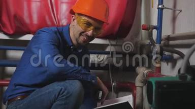 管道和传感器附近锅炉房工程师的肖像。 一个穿着硬帽子的<strong>男人</strong>微笑着看着