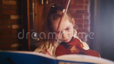 <strong>音乐课</strong>。 一个穿着白色毛衣的小女孩用音符演奏小提琴