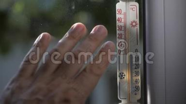 手指们触摸窗户，窗户贴在水银温度计上，显示外面32度的温度