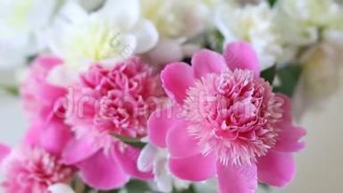 室内简易玻璃罐内的新鲜大珊瑚、粉红色、白色和奶油牡丹花束。 美丽的花瓶