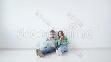 年轻的幸福夫妇正坐在空荡荡的房间里，打算在新房子里布<strong>置家</strong>具