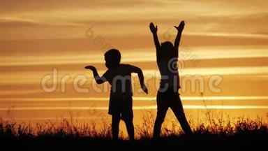 两个孩子在日落时跳舞，享受<strong>大自然</strong>。 幼儿`的剪影.. 快乐的孩子玩得开心，享受<strong>大自然</strong>。