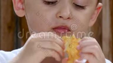 一个孩子坐在木墙背景下的桌子旁吃薯条。 嘴宝宝特写..