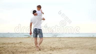 一个人扛着一个孩子，走向大海。 一家人住在沙滩上。 小男孩笑了