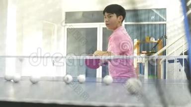 亚洲少年从机器人乒乓球机练习乒乓球，