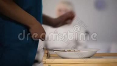 年轻护士为年老的残疾女士提供晚餐，照顾病人