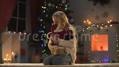 孤独可爱的女孩坐在闪闪发光的圣诞树和花环附近，<strong>想念</strong>父母