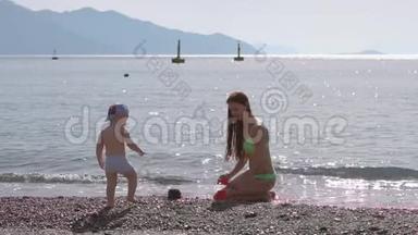 年轻女子在海边的沙滩上慢动作地和儿子玩耍