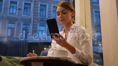 有智能手机的女商人用圆珠笔写字