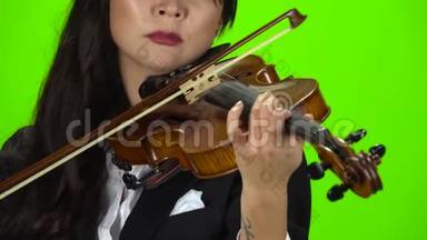 女人用手指弹奏小提琴。 快关门。 绿色屏幕