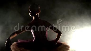 一个穿着芭蕾舞裙的年轻芭蕾舞女将双手伸向两侧，将双手握在重物上，将双手举过头顶