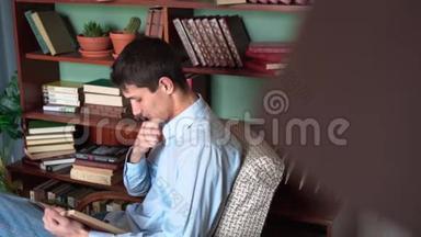 一个年轻人坐在家里的<strong>图书馆</strong>里<strong>看书</strong>，一个穿着蓝色衬衫和牛仔裤的人拿着一本书<strong>看书</strong>。