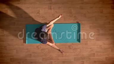 顶级射击，白种人正在冥想一个蓝色的瑜伽垫，放松和享受过程，深深地集中在木地板上