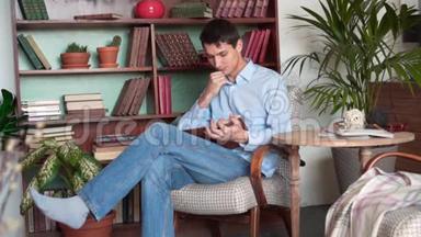一个年轻人坐在家里的图书馆里看书，一个穿着蓝色衬衫和牛仔裤的人拿着一本书看书。