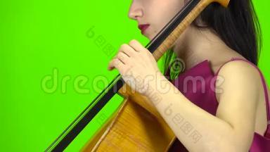 女孩用手指钉大提琴。 绿色屏幕。 侧视。 关门