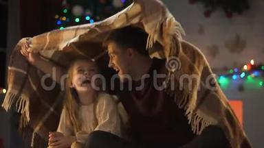 快乐的女孩听爸爸的故事，<strong>坐在</strong>闪闪发光的圣诞<strong>树下</strong>