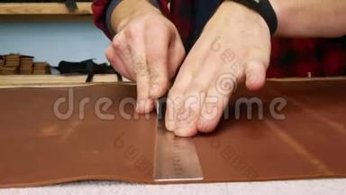 工匠用办公刀切割一张真皮。 手工制造的。 关门