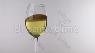 运动的白酒在酒杯中站在白色的背景上，特写..