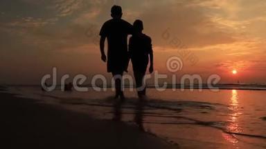 日落时在海滩上的父子。快乐的小家庭在海滩上玩得开心。日落时奔跑跳跃