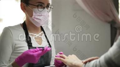 指甲修剪专家给客户。 指甲美容师把指甲送到指甲沙龙里的女人身上。 高加索女人