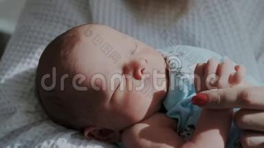 特写镜头甜蜜沉睡的小宝宝.. 新生儿在梦中移动他的眼睛。 家长握着保姆的手