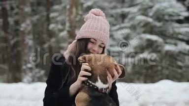 快乐的美丽的年轻女子戴着粉红色的帽子，在冬天抚摸她的比格犬。 友谊，宠物和人类。 候选人和候选人