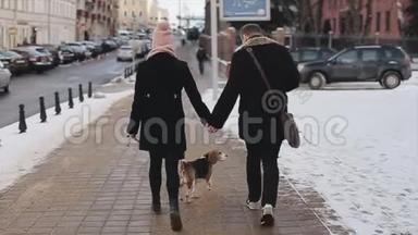 年轻时尚夫妇在街上遛狗的后景。 男人和女人在一起快乐。 小猎犬。 秋季