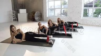 健美操运动在健身课上用橡皮筋在地板上排成一排年轻女子组。 体育运动健康生活方式