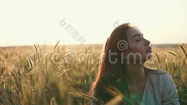 放松的黑发女人正坐在田野上，夕阳下，她的耳朵是金色的黑麦