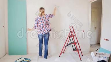慢镜头的快乐年轻女子跳舞时，在她的公寓<strong>墙画</strong>。 年轻女孩正在装修