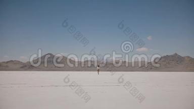 在犹他州邦纳维尔的一个平坦的盐漠湖，一个女人在沸腾的高温下独自<strong>远离</strong>镜头的镜头。